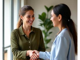 Two diverse individuals smiling and shaking hands, symbolizing successful peer connection and support.